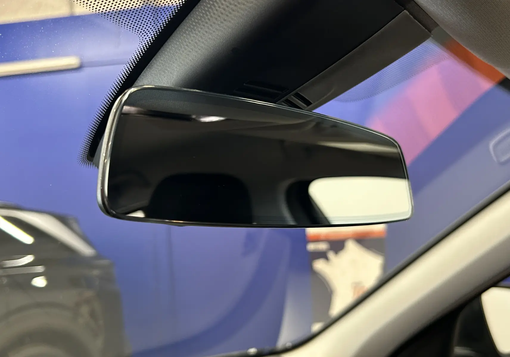 Rétroviseur intérieur de BMW Série 1 16d 116ch noir, vue rapprochée avec reflet flou du tableau de bord.