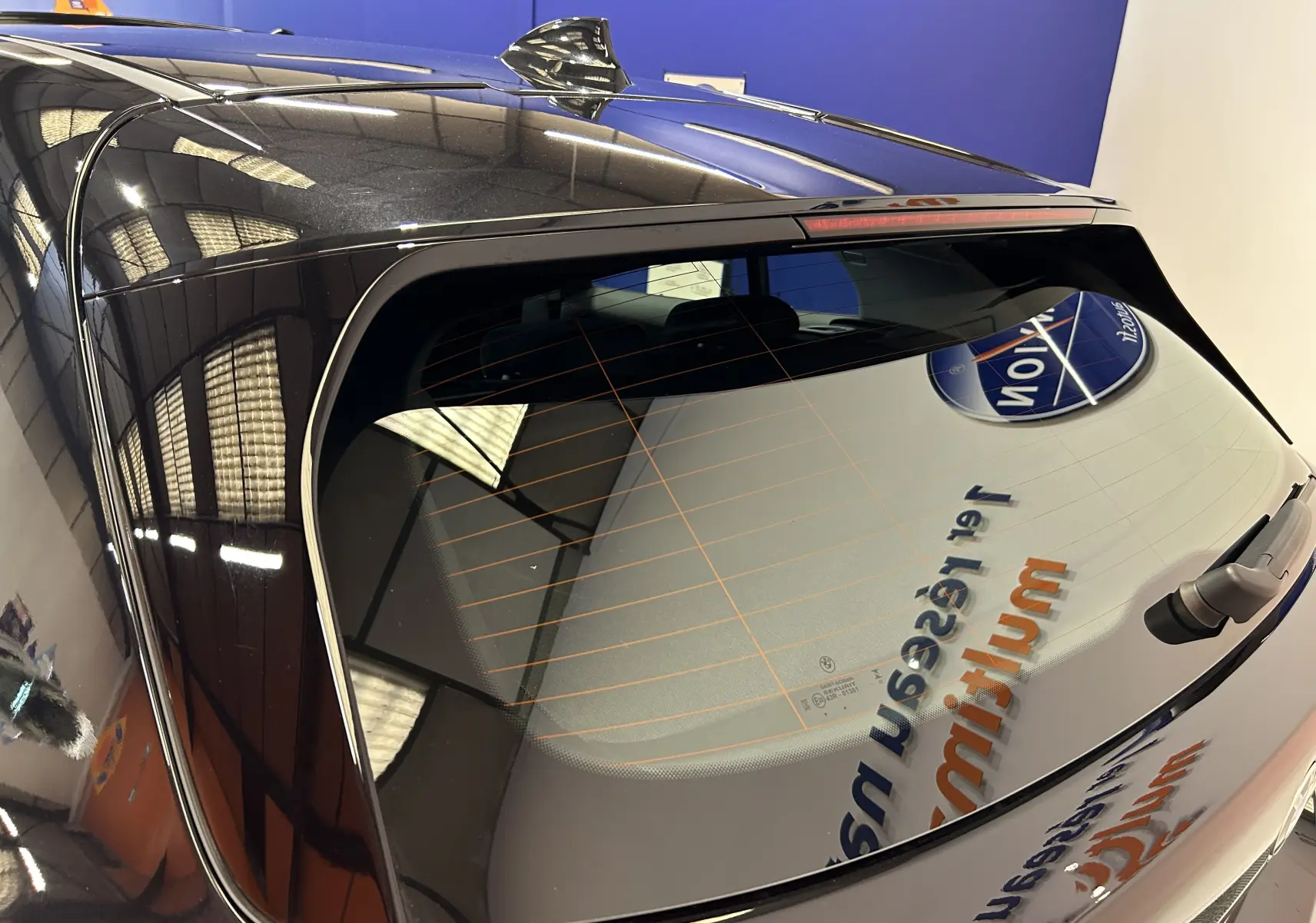 Vue arrière en plongée d'une BMW Série 1 noire 5 portes avec lunette arrière et antenne requin visibles.