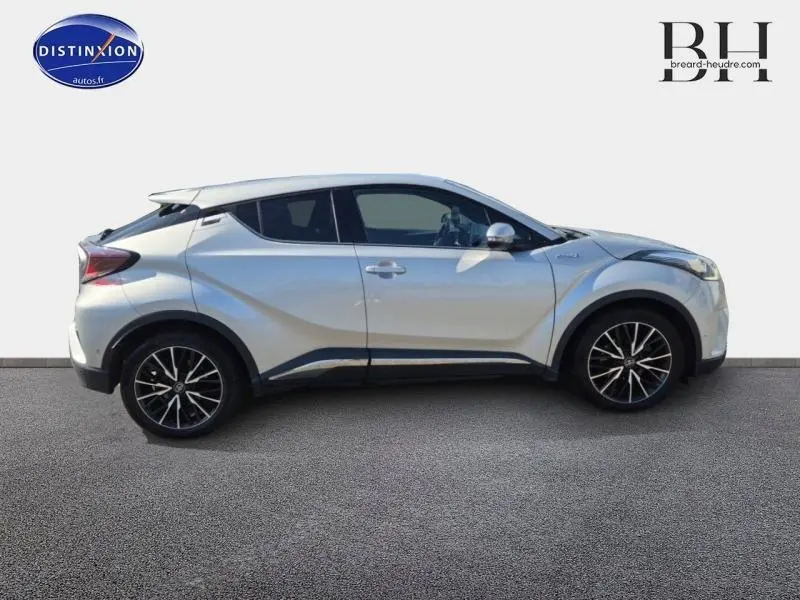 Profil côté gauche d'un Toyota C-HR 122h Distinctive gris aluminium avec jantes alliage et lignes anguleuses marquées.