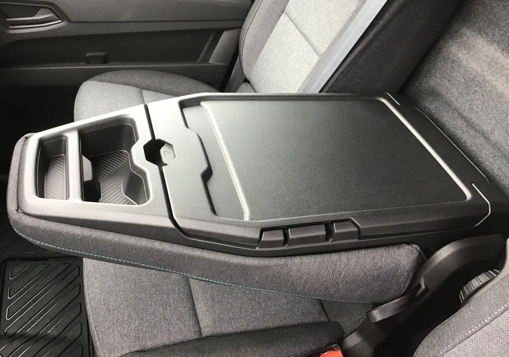 Vue rapprochée de la banquette passager gris urbain du Renault Master L2H2 avec bureau mobile intégré et porte-gobelets.