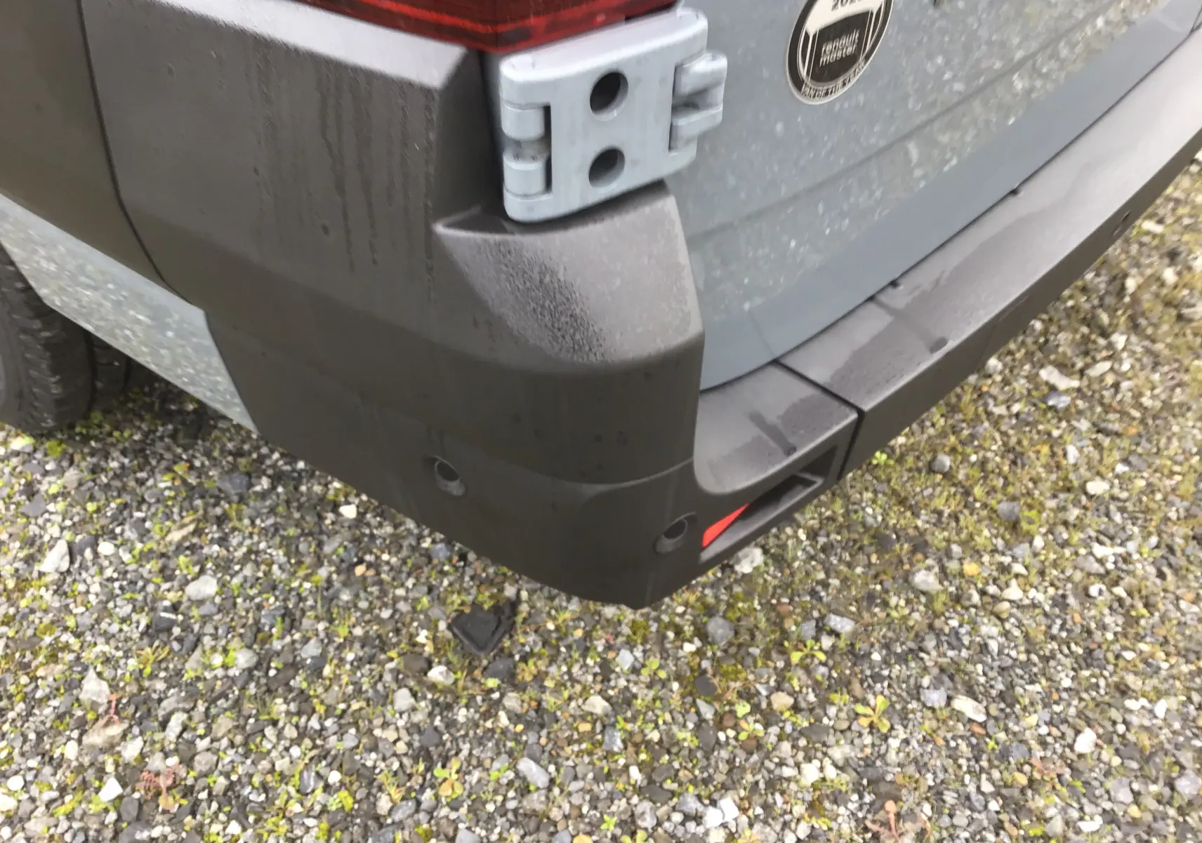 Gros plan sur l'angle arrière droit du Renault Master gris urbain 2025, montrant le pare-chocs et la charnière de porte.
