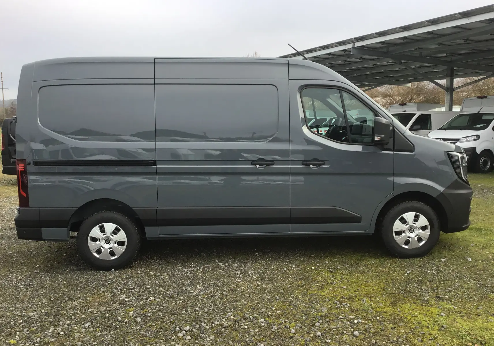 Vue de profil côté gauche d’un Renault Master L2H2 gris urbain, fourgon utilitaire avec jantes acier et rétroviseurs noirs.