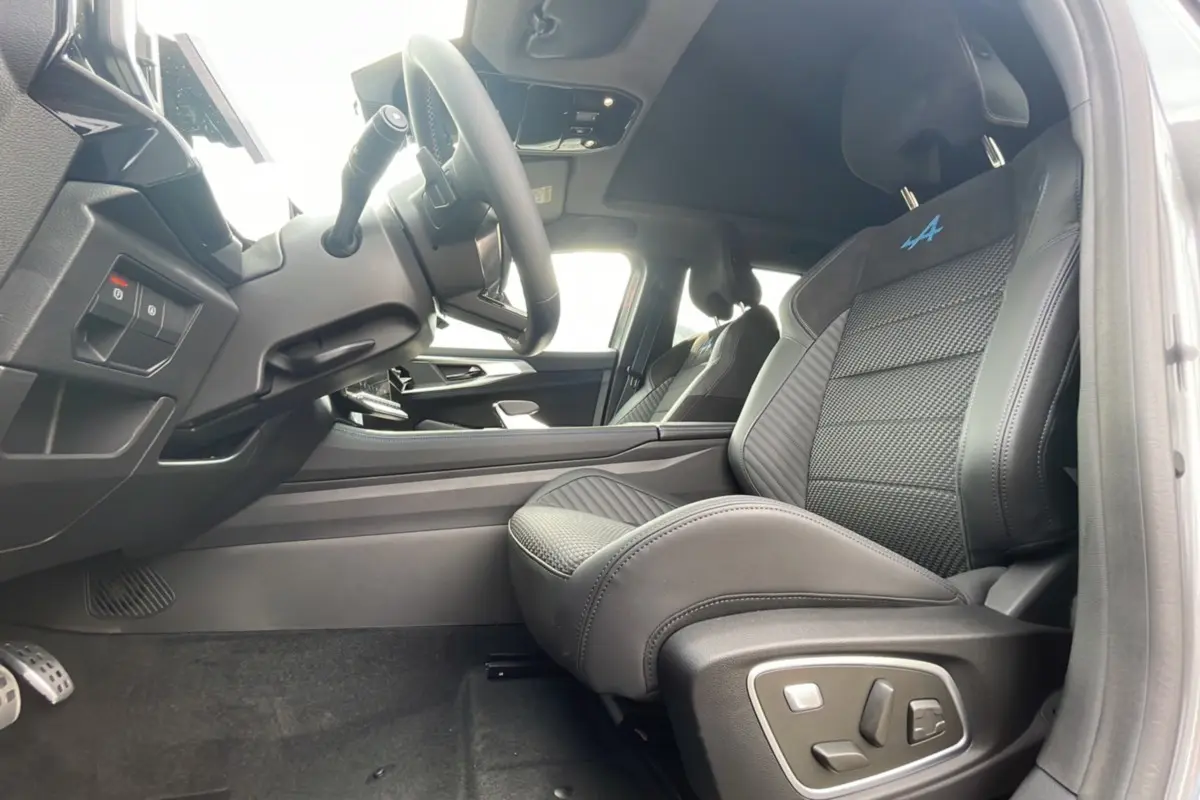 Intérieur côté conducteur du Renault Austral gris schiste, sièges sport semi-alcantara avec logo Alpine bleu et toit panoramique visible.