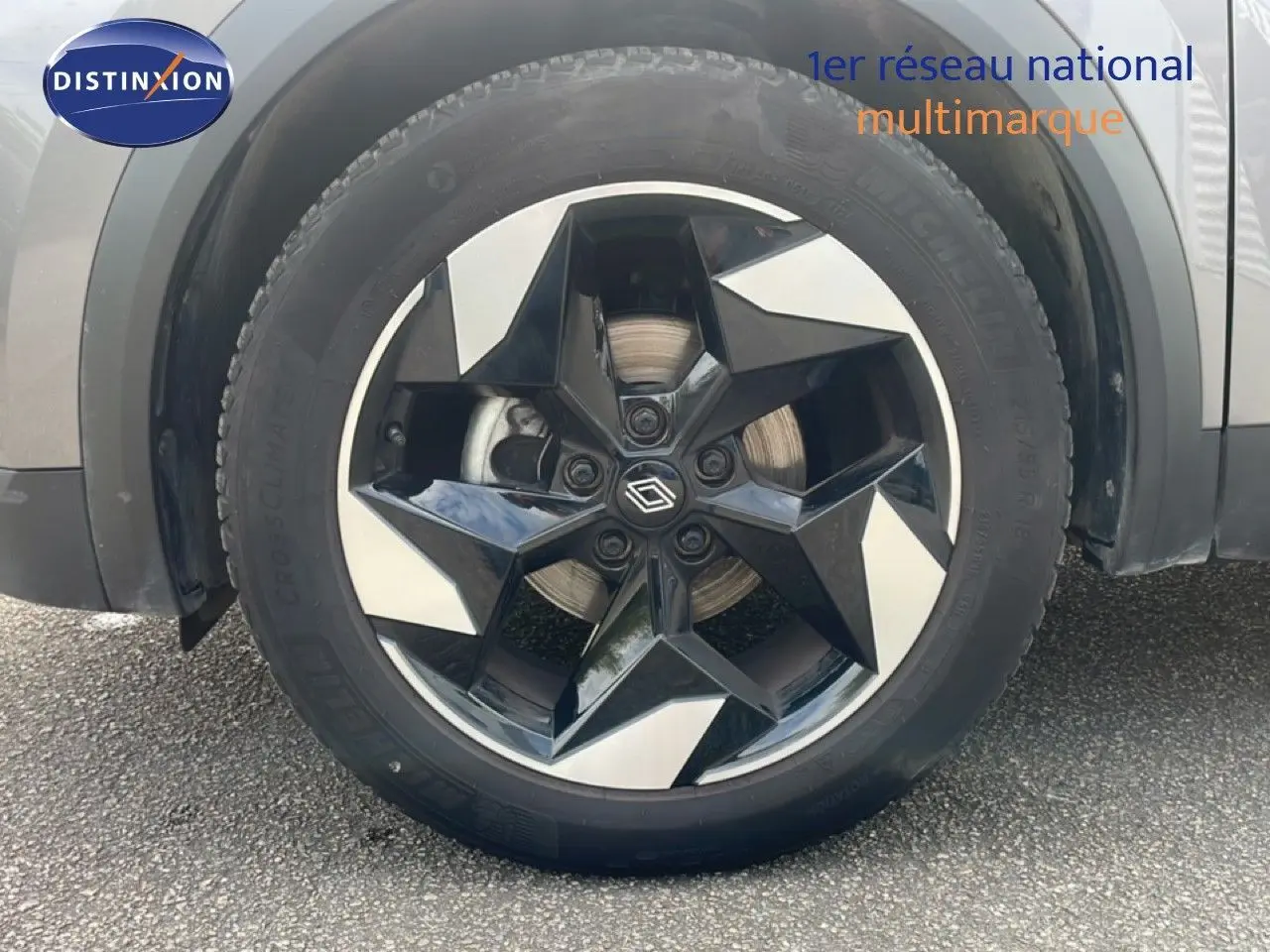 Gros plan sur la roue avant gauche du Renault Captur gris Cassiopée métal avec jante noire et argentée en étoile.