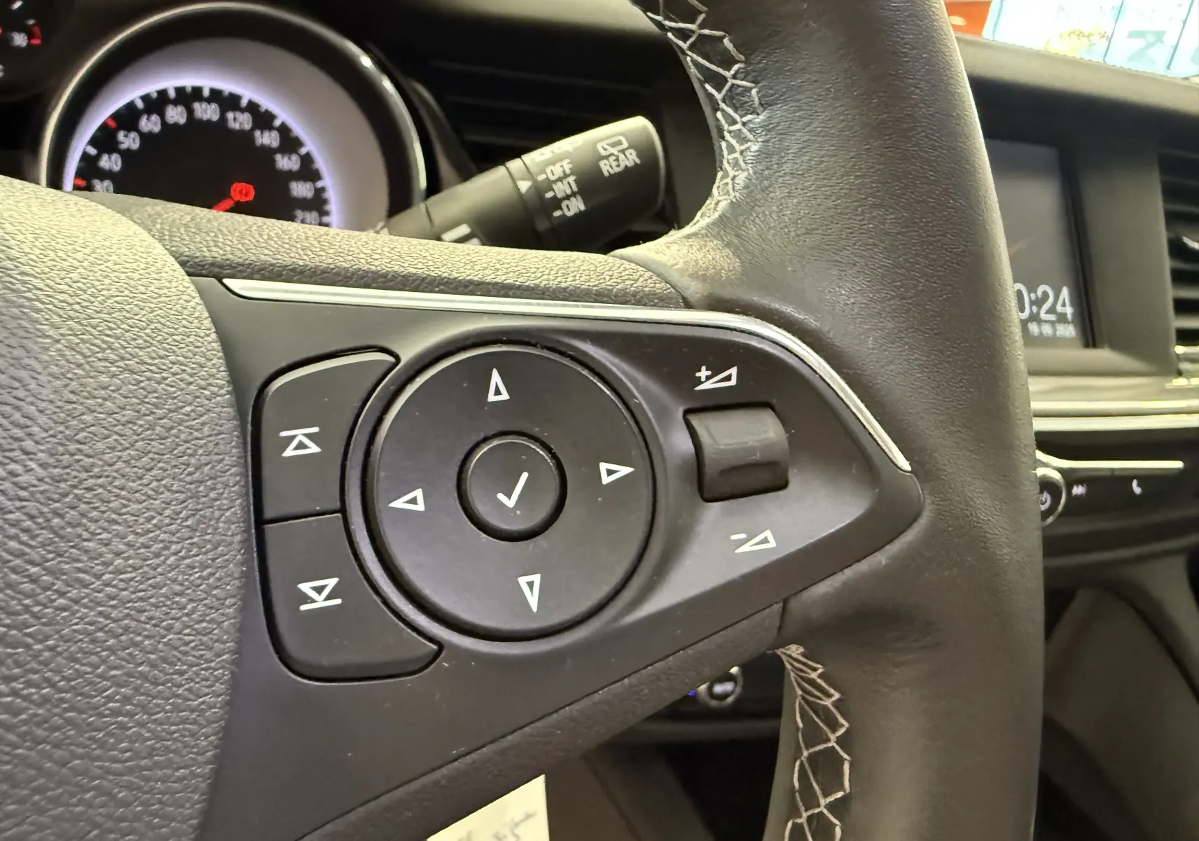 Gros plan sur les commandes du volant en cuir noir de l'Opel Insignia Sports Tourer 2019, tableau de bord en arrière-plan.