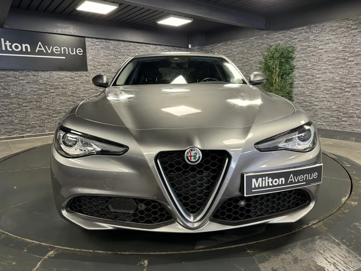 Vue frontale d'une Alfa Romeo Giulia gris métallisé avec calandre emblématique en V et phares LED distinctifs.