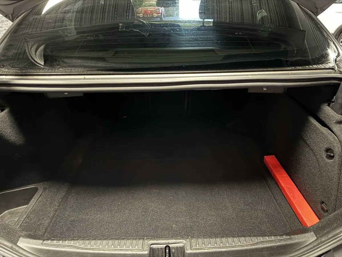 Coffre ouvert d'une Alfa Romeo Giulia gris 2021, montrant un espace de chargement vide avec un triangle de signalisation rouge.