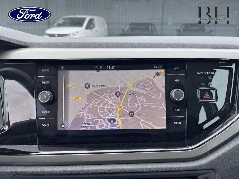 Vue intérieure du tableau de bord avec écran tactile affichant la navigation d'une Volkswagen Polo blanche, version 2021.