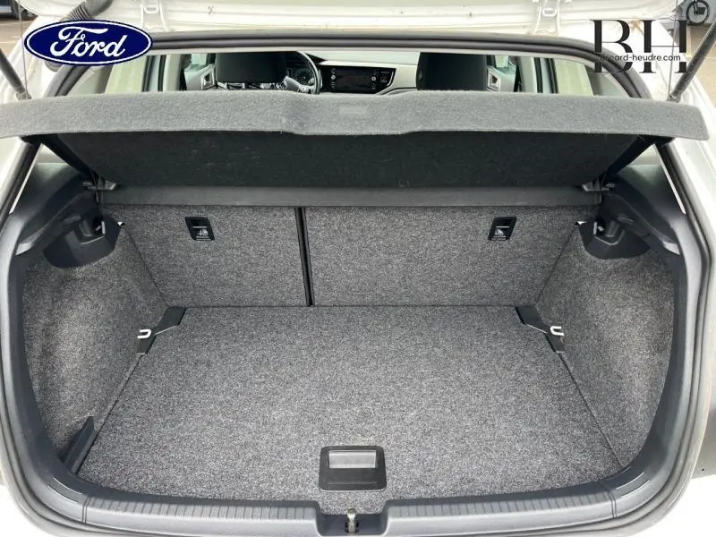 Vue intérieure du coffre ouvert d'une Volkswagen Polo blanche, montrant un espace de rangement propre et bien fini.