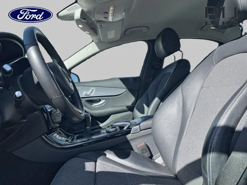 Vue intérieure côté conducteur de la Mercedes Classe C 200 d Business 2016 avec sièges noirs et volant multifonction.