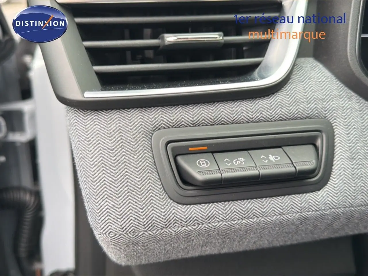 Détail du tableau de bord de la Renault Clio 2025, bouton de réglage éclairage sur habillage tissu gris à chevrons.