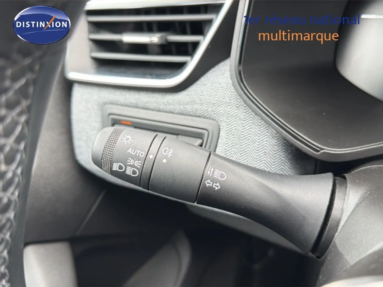 Gros plan sur la commande des phares et clignotants dans l’habitacle gris noir de la Renault Clio hybride 2025.