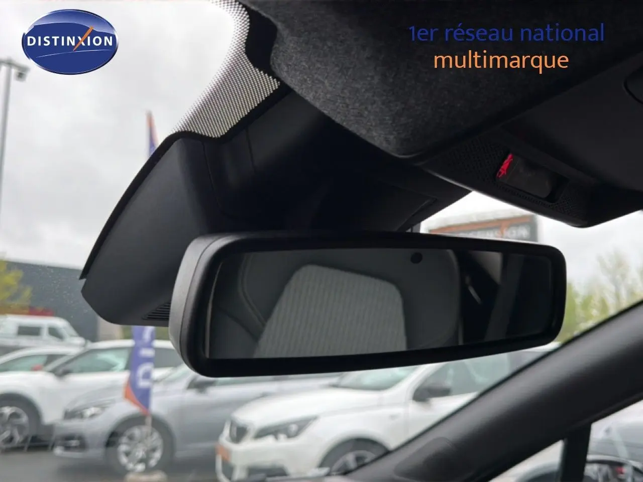 Vue intérieure centrée sur le rétroviseur intérieur d’une Renault Clio gris Rafale Metal, avec siège en tissu visible en reflet.