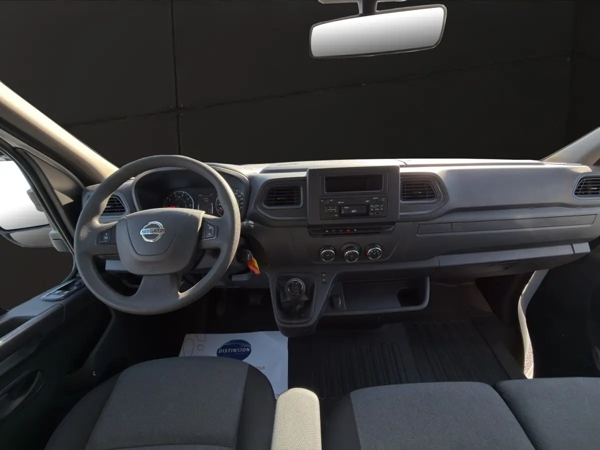 Vue intérieure du tableau de bord et volant du Nissan Interstar 2024, avec commandes manuelles et écran central.