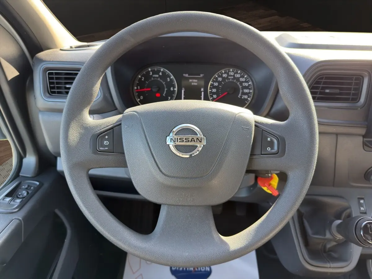 Vue centrée sur le volant multifonctions gris du Nissan Interstar 2024 avec tableau de bord et levier de vitesse manuel.