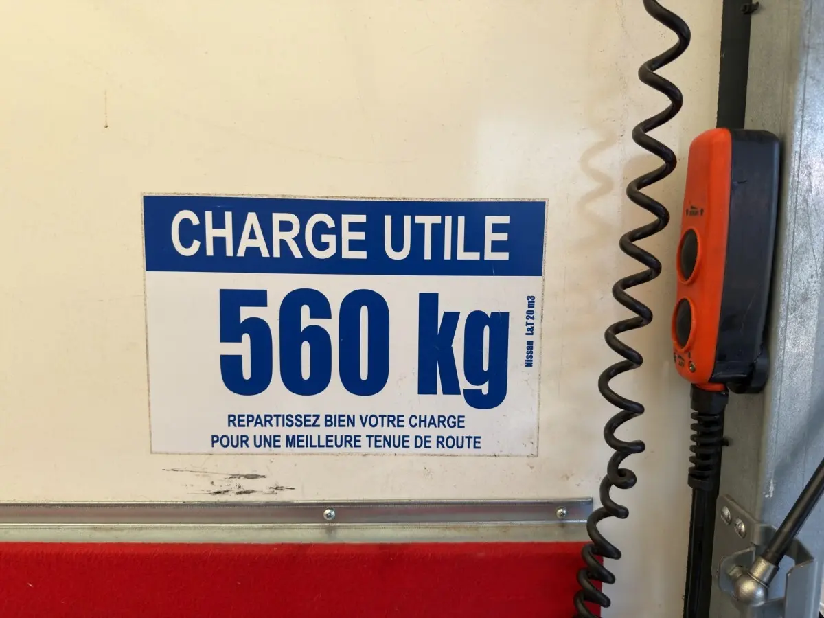 Vue intérieure du hayon d’un utilitaire Nissan Interstar blanc, avec étiquette de charge utile 560 kg et commande rouge.