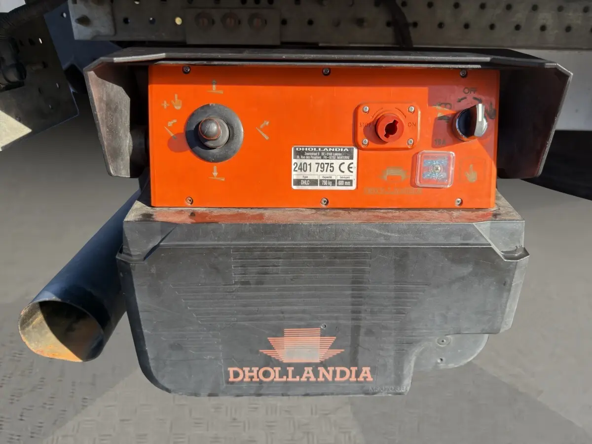 Gros plan sur le boîtier de commande orange et noir du hayon Dhollandia fixé à l'arrière du Nissan Interstar blanc.