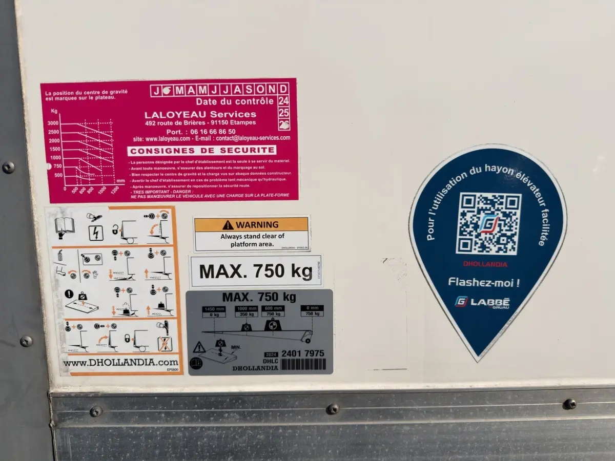 Gros plan sur des autocollants de sécurité et d’utilisation du hayon élévateur sur la caisse blanche d’un Nissan Interstar.