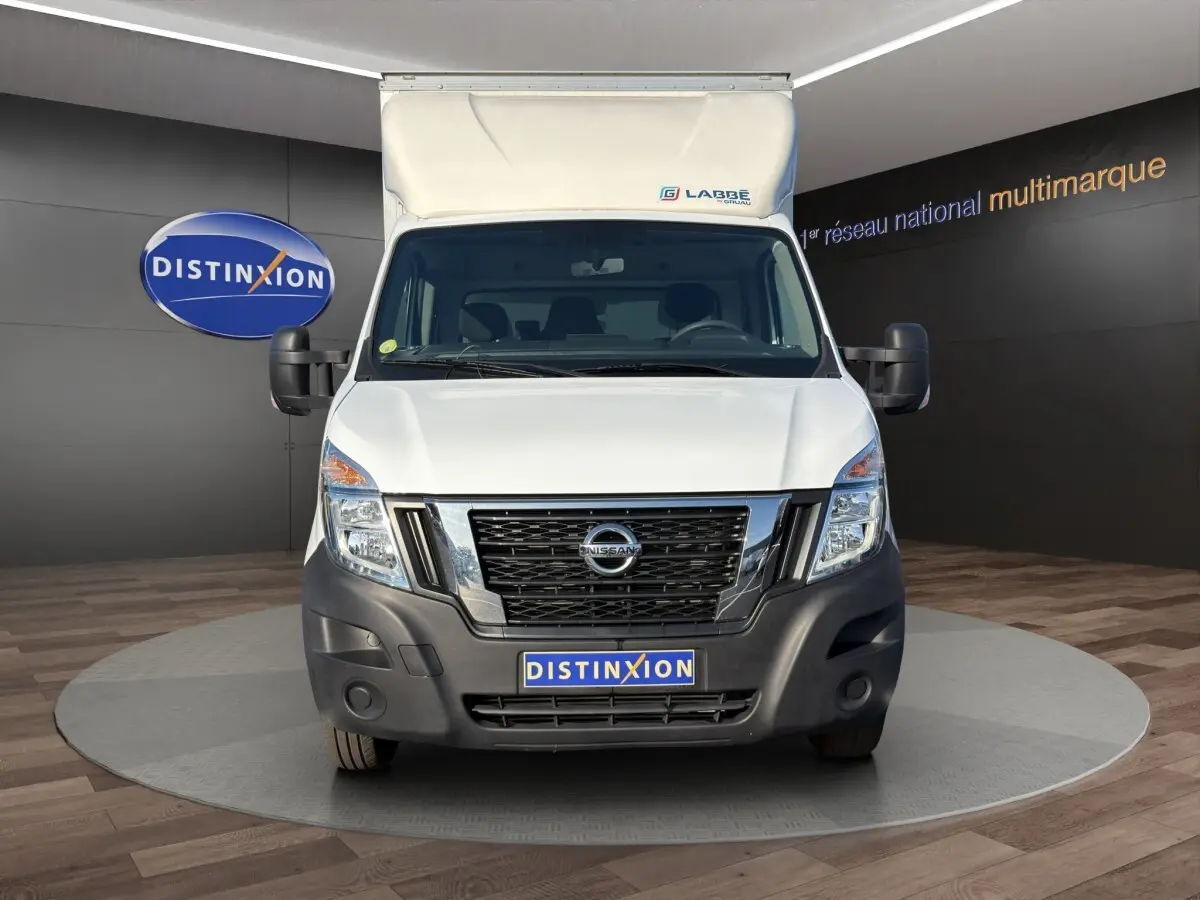 Vue de face du utilitaire blanc Nissan Interstar avec caisse surélevée et pare-chocs noir, en showroom Distinxion.