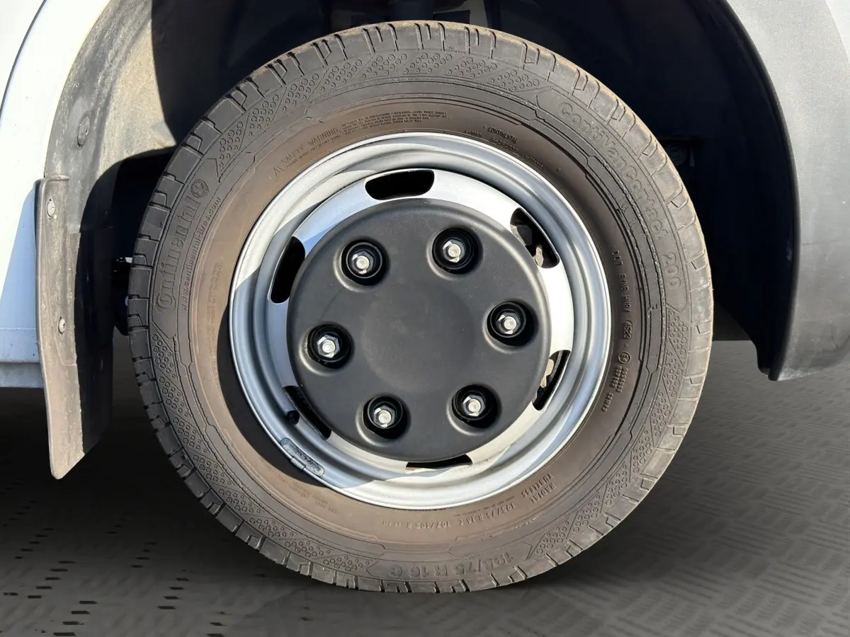 Gros plan sur la roue jumelée avant droite du Nissan Interstar blanc, jante acier avec cache central noir.