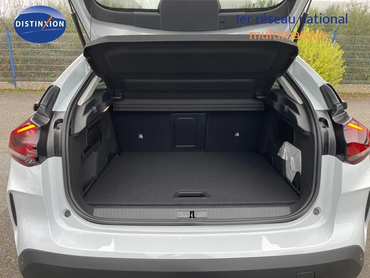 Coffre ouvert vu de l'arrière d'une Citroën C4 blanche métal 2024, montrant l'espace de chargement vide.