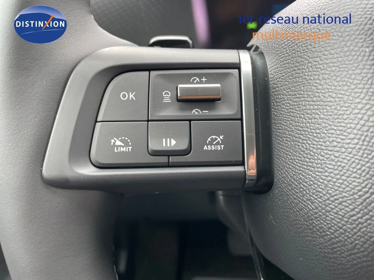 Gros plan sur les commandes au volant de la Citroën C4 blanche métal 2024, avec boutons d'assistance et limitation de vitesse.