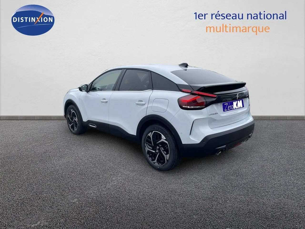 Vue 3/4 arrière droite d'une Citroën C4 blanche métal avec toit noir et jantes bicolores sur fond neutre.