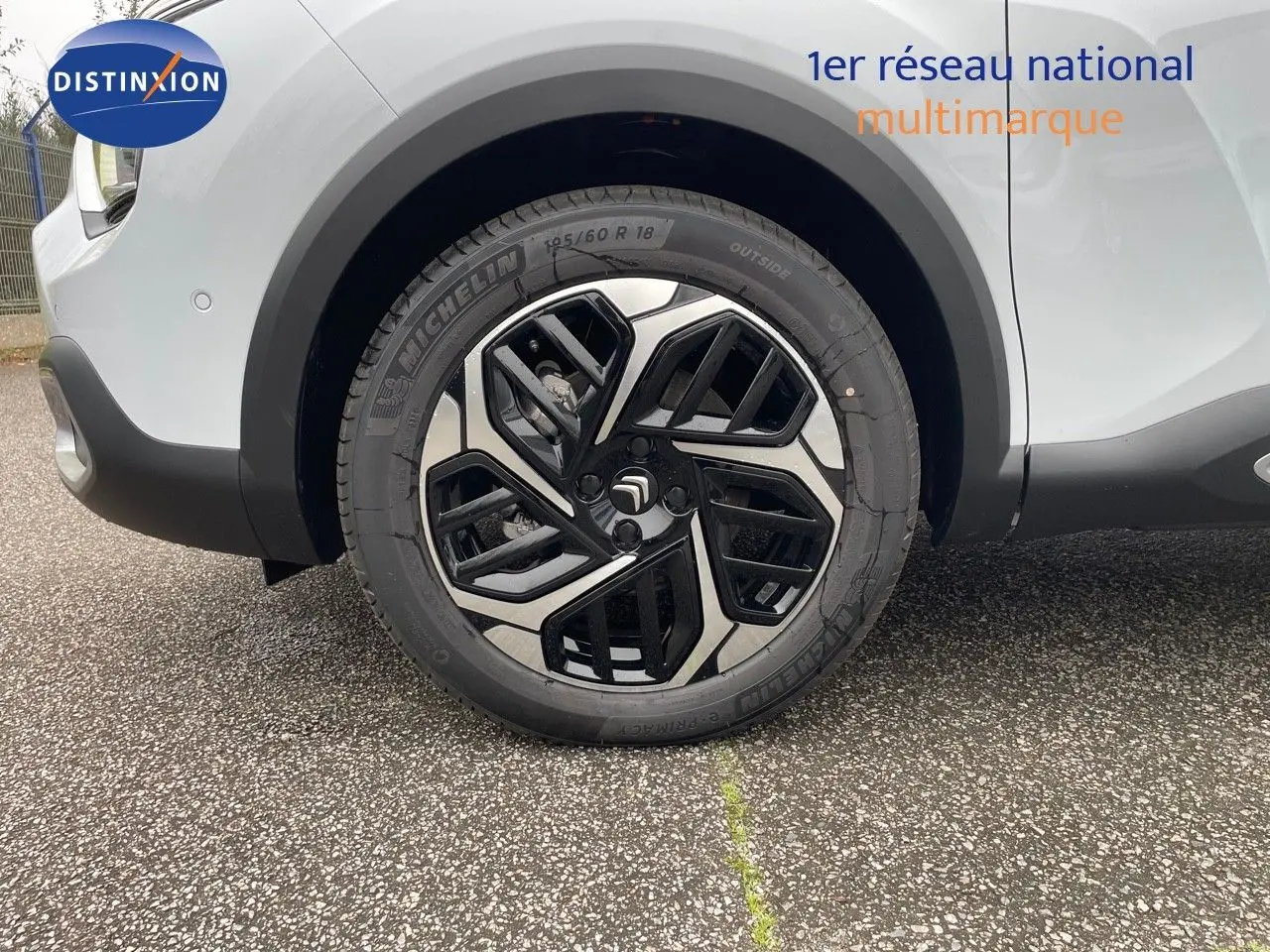 Gros plan sur la roue avant gauche d'une Citroën C4 blanche métal 2024 avec jante alliage bi-ton noire et argent.