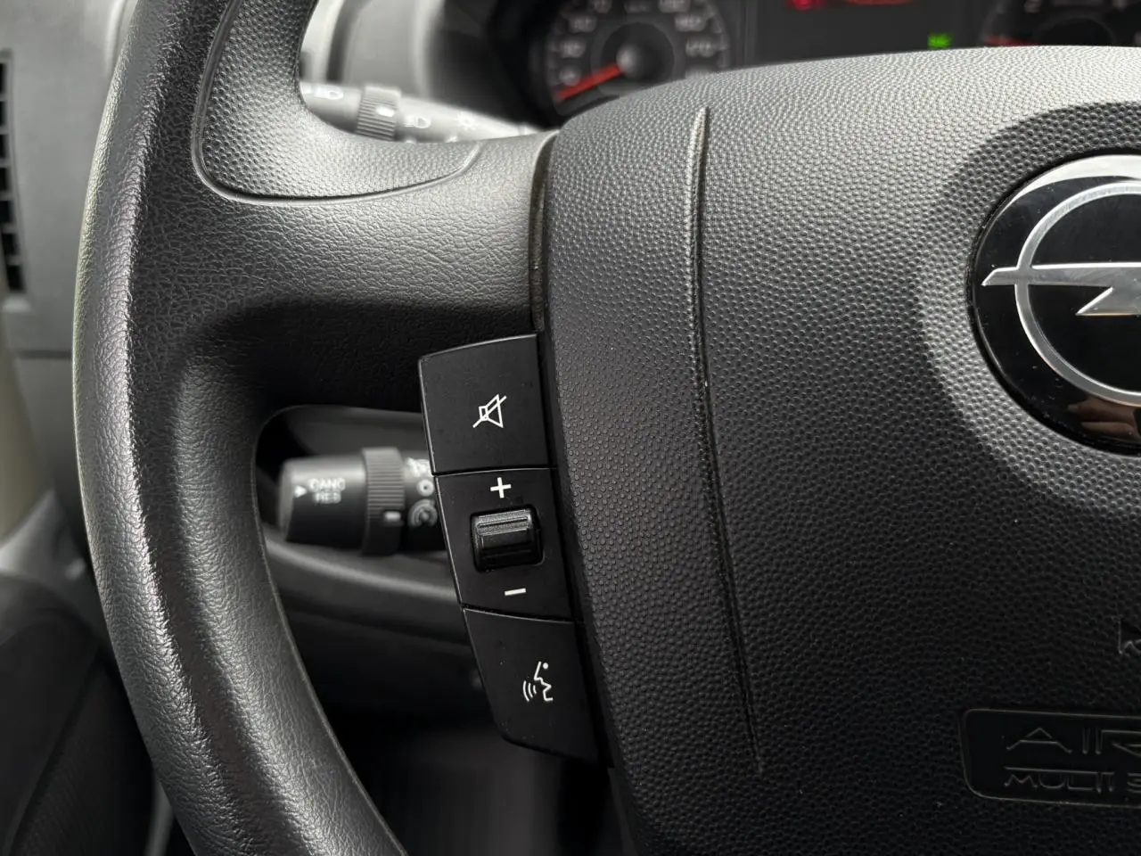 Gros plan sur le volant noir de l'Opel Movano Fourgon 2023 avec commandes audio intégrées visibles.