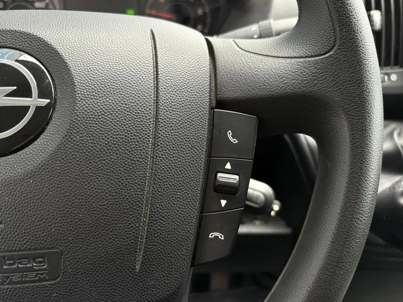 Gros plan sur le volant noir de l'Opel Movano Fourgon 2023 avec commandes d'appel intégrées.