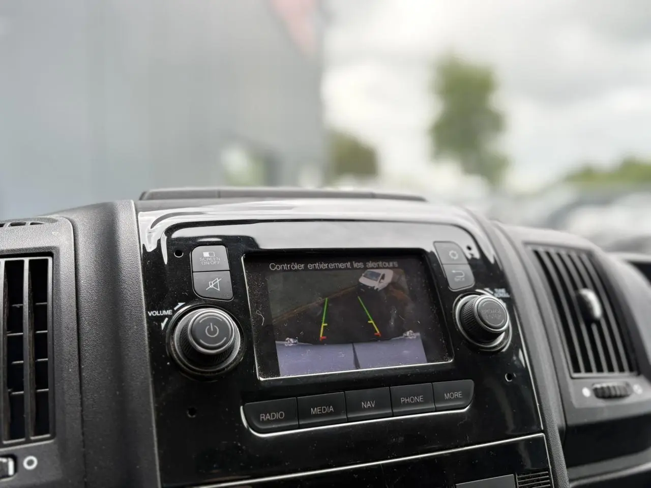 Écran tactile central affichant la caméra de recul du tableau de bord noir de l'Opel Movano Fourgon blanc 2023.