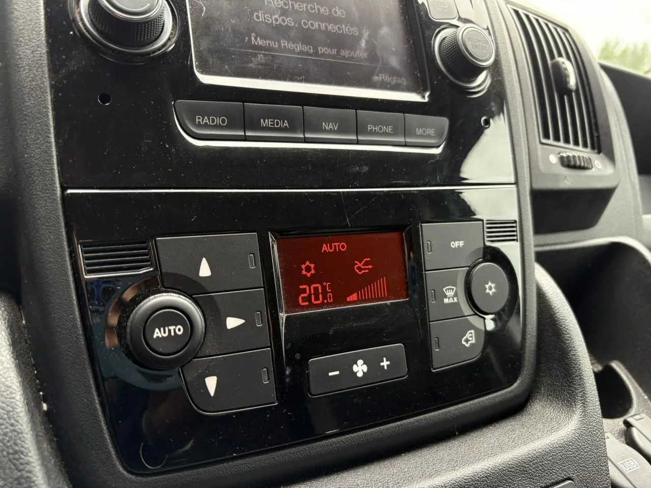 Vue rapprochée du tableau de bord noir de l'Opel Movano Fourgon 2023, mettant en valeur la climatisation automatique réglée à 20°C.