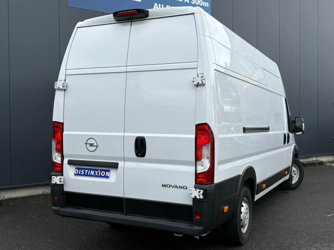 Vue 3/4 arrière droite d'un utilitaire Opel Movano Fourgon blanc avec portes arrière battantes et feux rouges visibles.