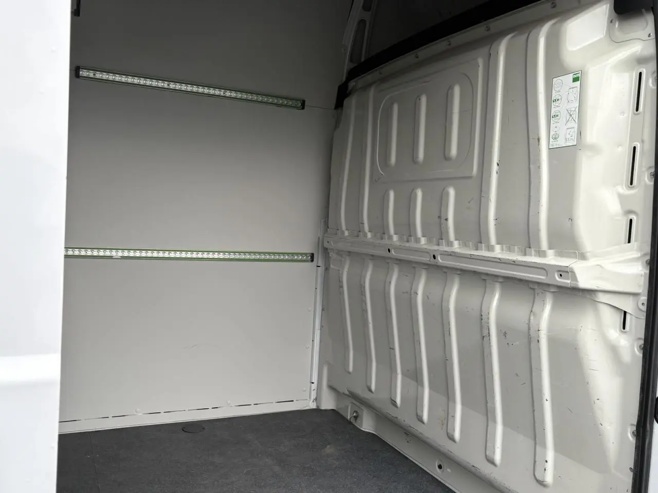 Vue intérieure arrière droite du fourgon Opel Movano blanc avec plancher bois et habillage latéral tôlé.