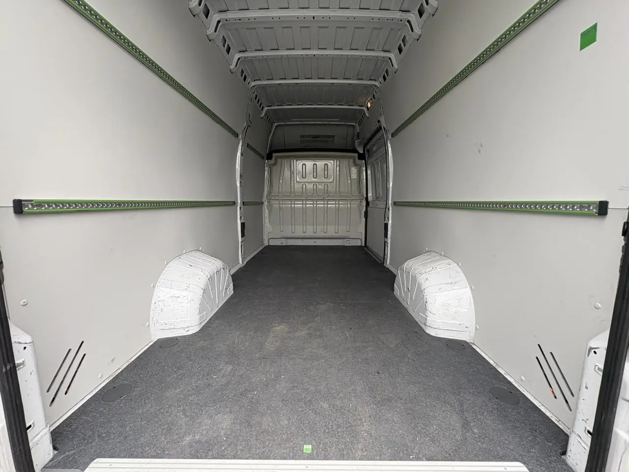 Intérieur du fourgon Opel Movano blanc, vue de l'espace de chargement avec plancher bois et habillage latéral.