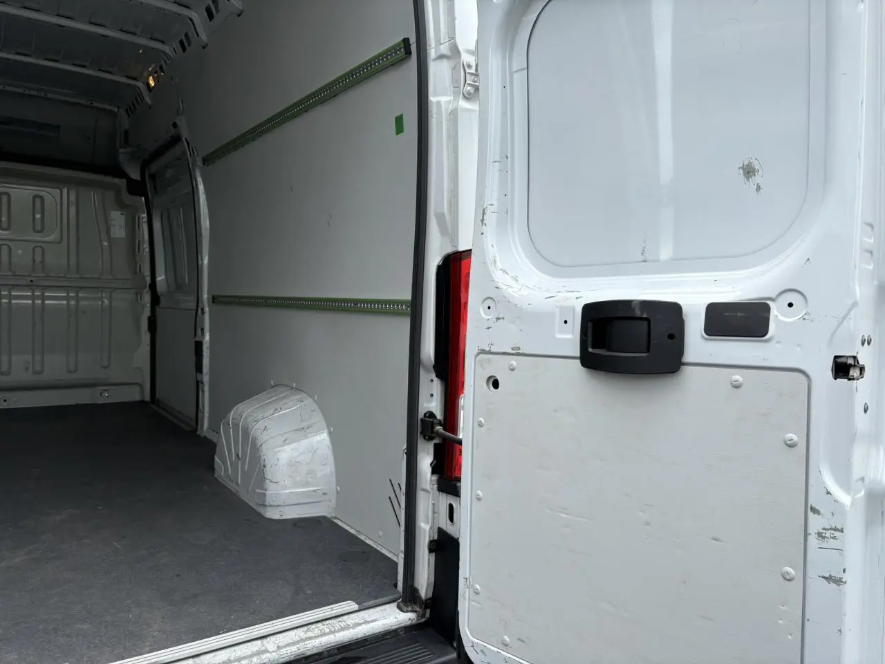 Vue intérieure arrière du fourgon blanc Opel Movano avec plancher et habillage latéraux visibles.