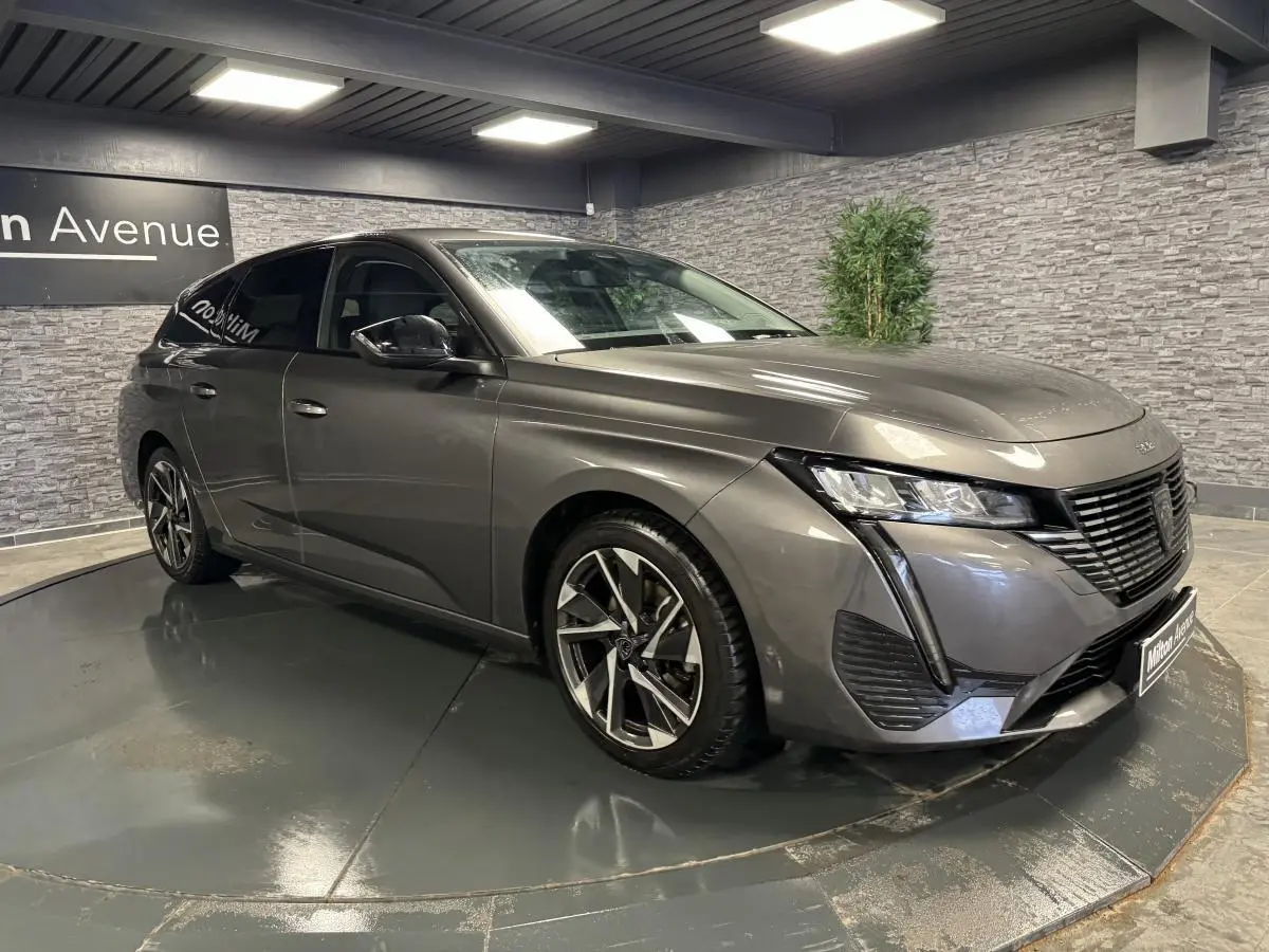 Peugeot 308 SW gris métallisé vue 3/4 avant droit avec calandre noire et jantes alliage 17 pouces.