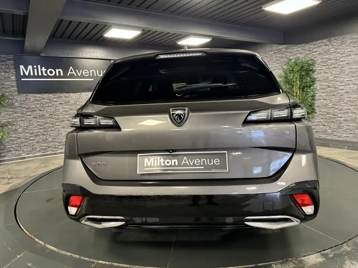 Vue arrière d'une Peugeot 308 SW gris métallisé avec feux LED et double sortie d'échappement chromée.