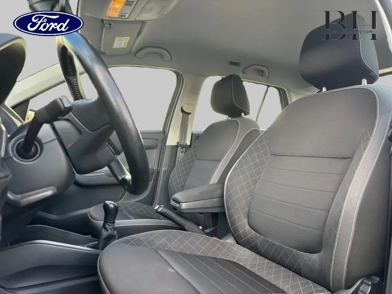 Intérieur avant de la Skoda Fabia 2021 avec sièges tissu noir et gris, volant cuir et accoudoir central visible côté conducteur.