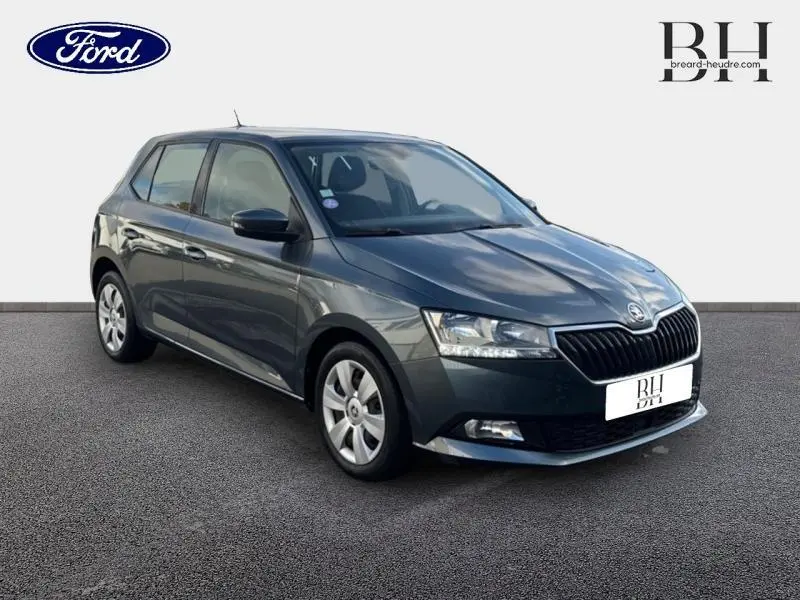 SKODA FABIA gris météore vue 3/4 avant droit, mettant en valeur sa calandre distinctive et ses phares LED.