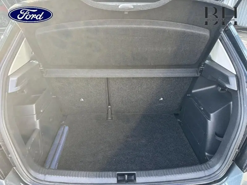 Coffre ouvert vu de l'arrière d'une voiture noire, montrant un espace de chargement propre et vide.