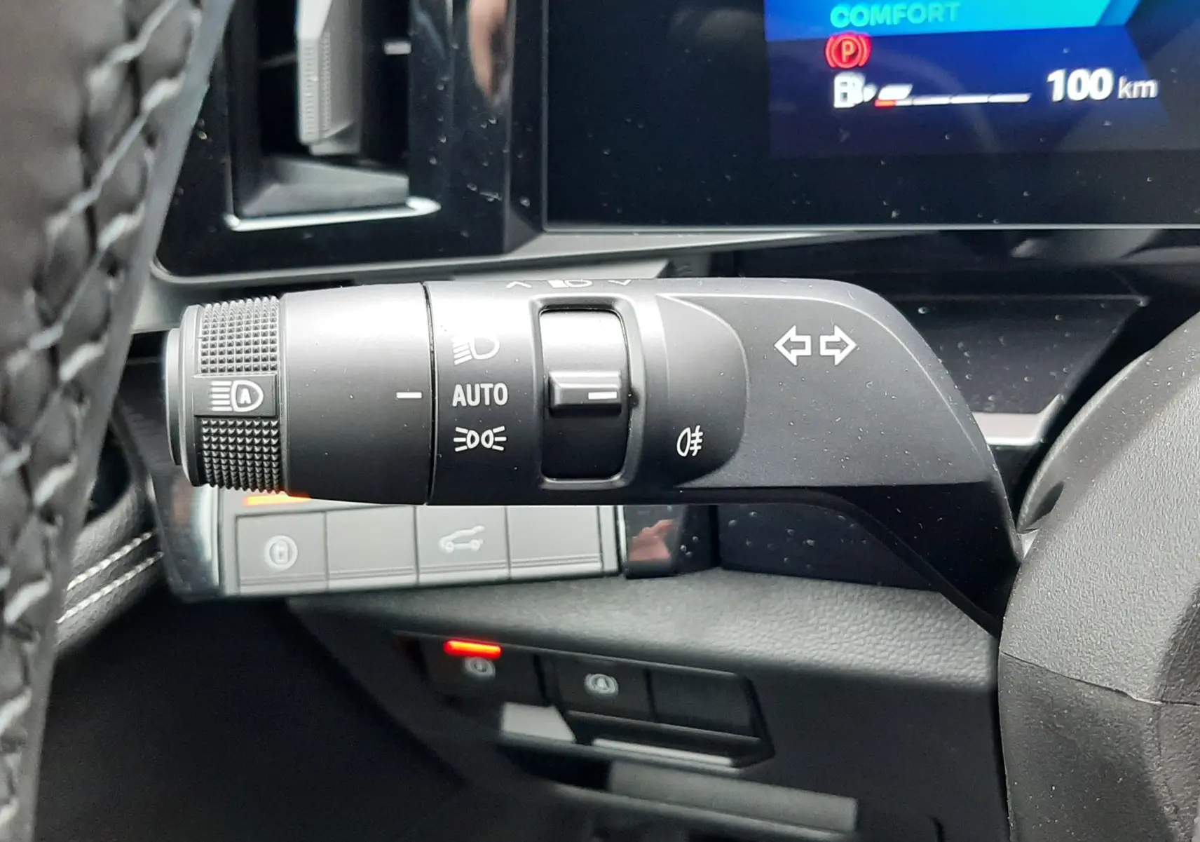 Gros plan sur la commande des feux et clignotants à gauche du volant du Renault Austral gris schiste, tableau de bord numérique en arrière-plan.