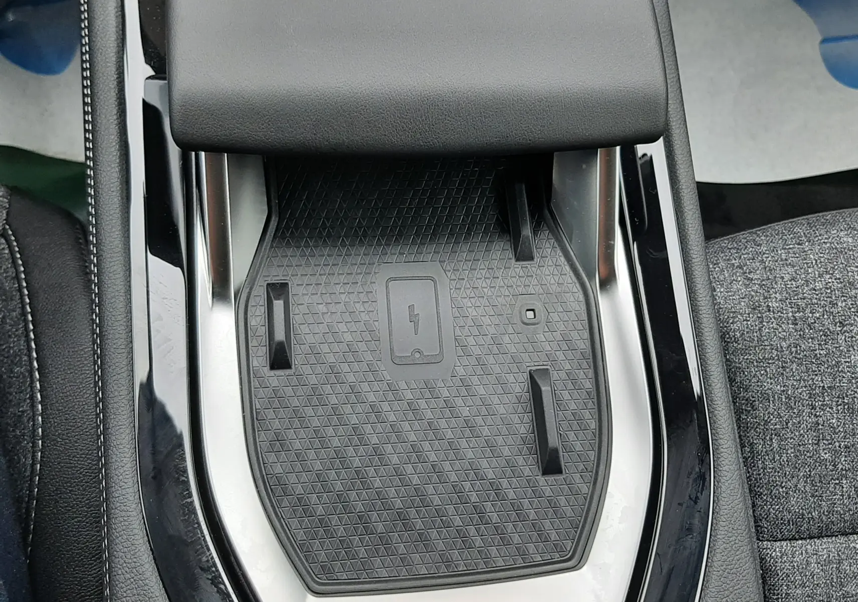 Gros plan sur la console centrale avec zone de charge sans fil du Renault Austral Ph.2 gris schiste, intérieur tissu gris.