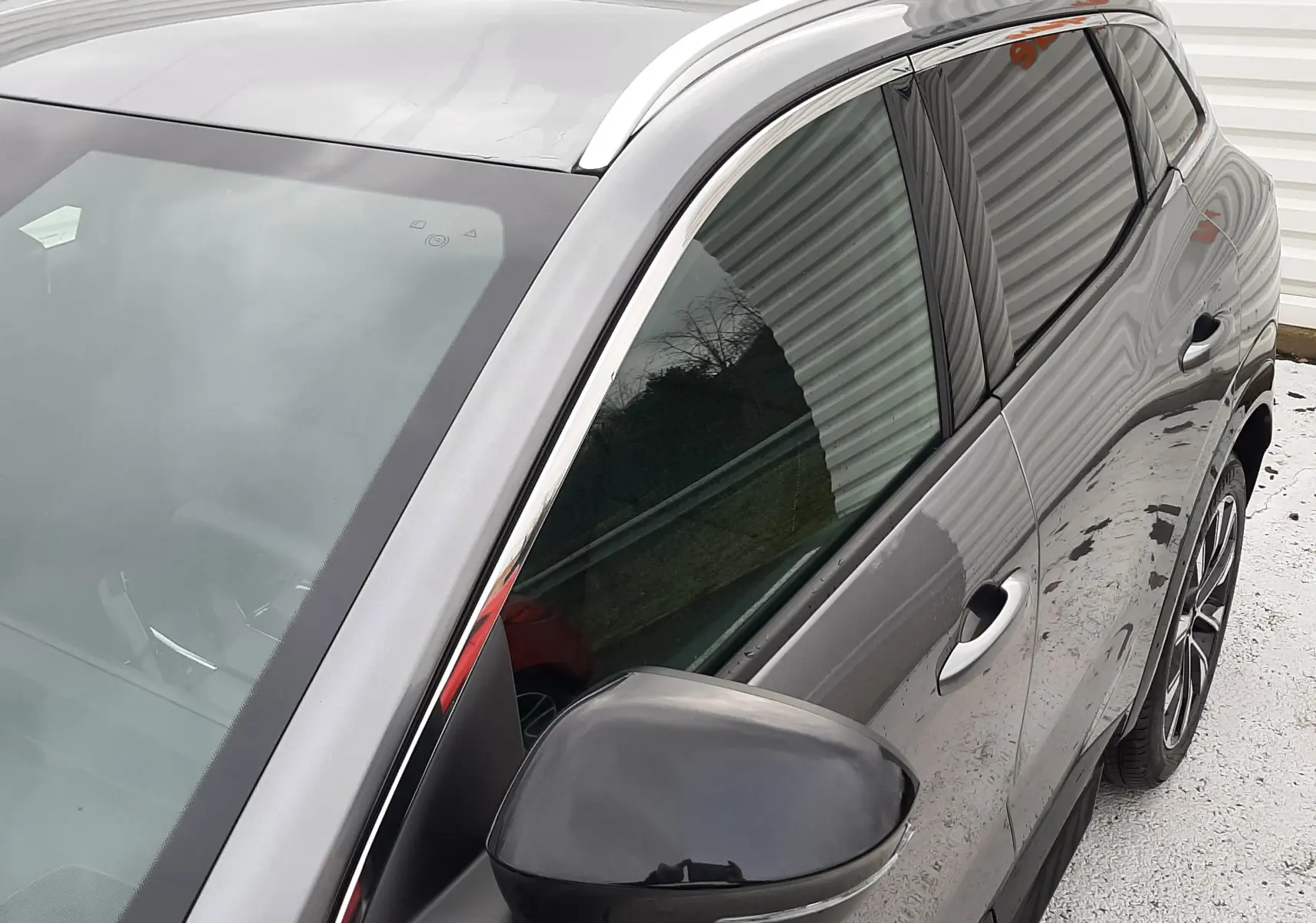 Vue 3/4 avant droit du Renault Austral gris schiste, mettant en valeur le rétroviseur noir et les vitres teintées.