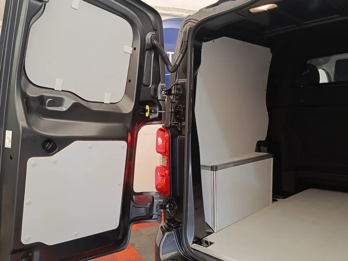 Vue intérieure arrière du Citroën Jumpy gris foncé, montrant la cloison pleine et l'espace de chargement aménagé.