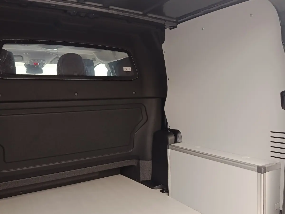 Vue intérieure arrière du Citroën Jumpy gris foncé, montrant la cloison vitrée pleine et l'espace de chargement.