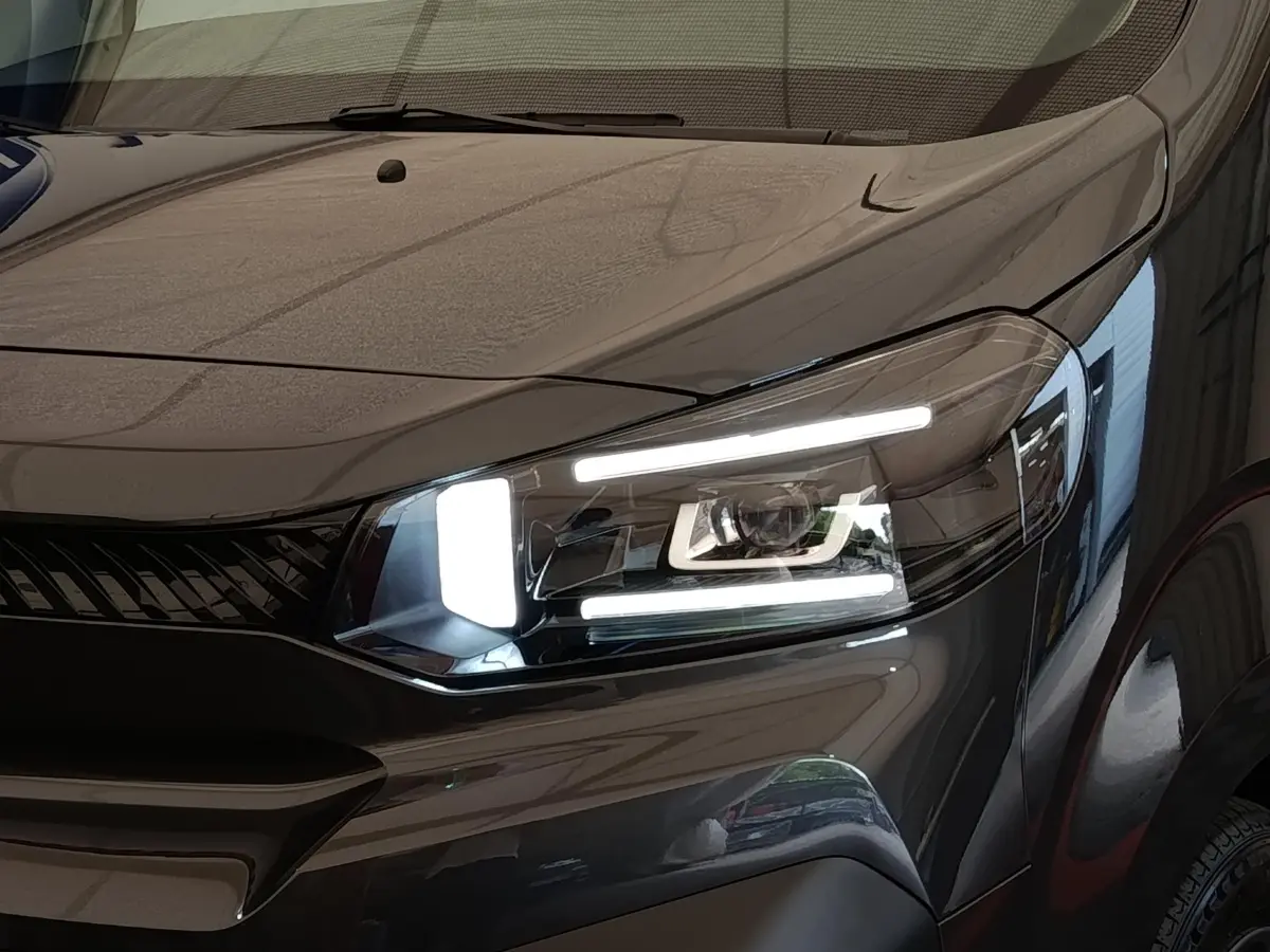 Gros plan sur le phare avant droit allumé d’un Citroën Jumpy gris foncé, soulignant son design moderne et lumineux.