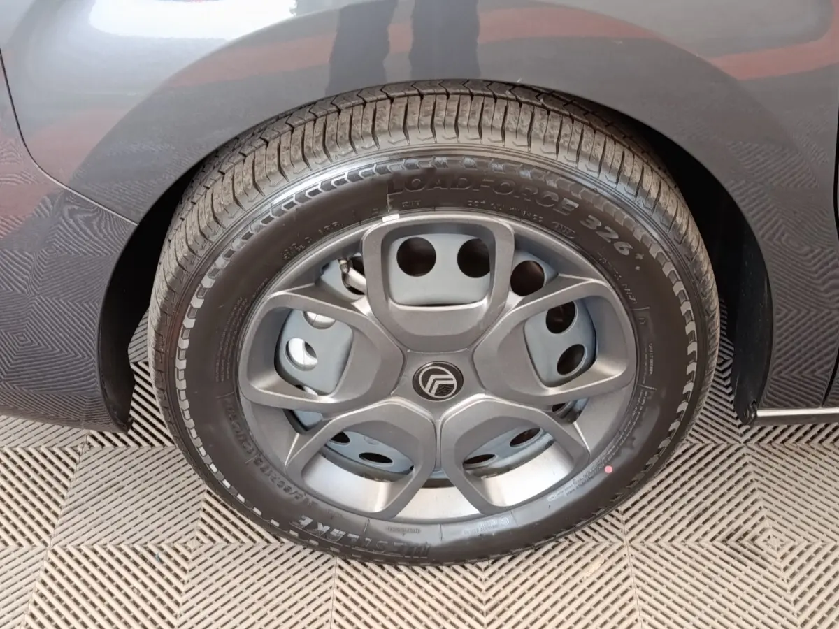 Gros plan sur la roue arrière droite d'un Citroën Jumpy gris foncé, mettant en valeur le pneu et l'aile du véhicule.