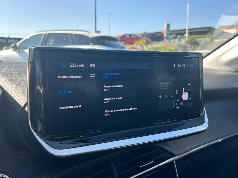 Écran tactile central du tableau de bord d'une Peugeot 208 gris 2024, affichant le menu assistant vocal.