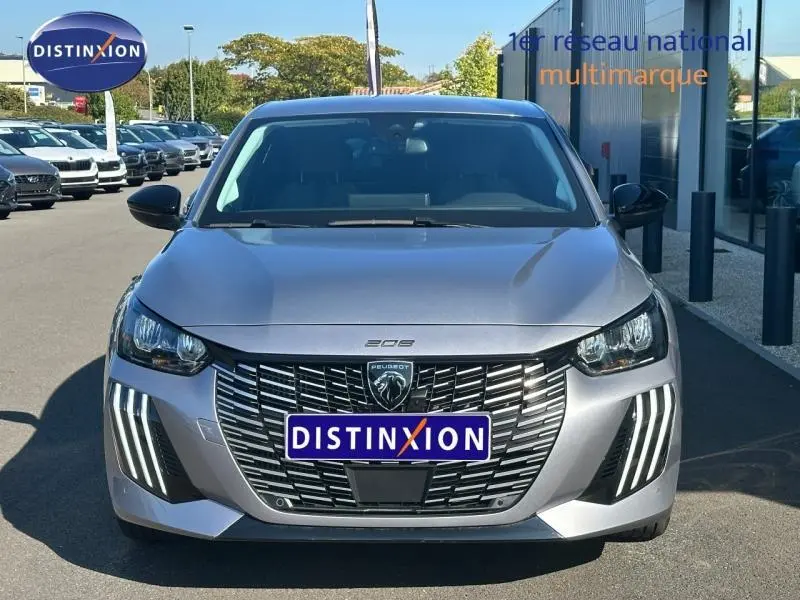 Vue frontale d'une Peugeot 208 gris métallisé 2024 avec calandre imposante et feux LED en forme de griffes distinctives.